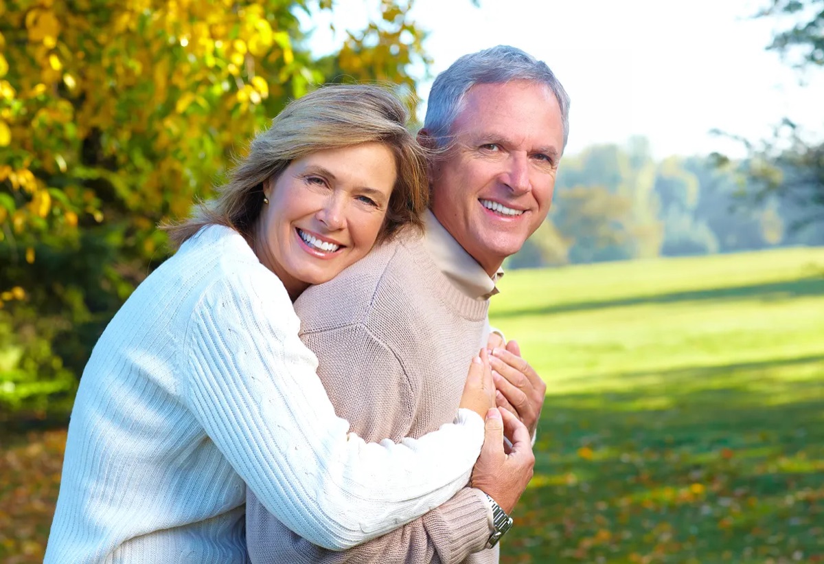 An older couple embracing in a park