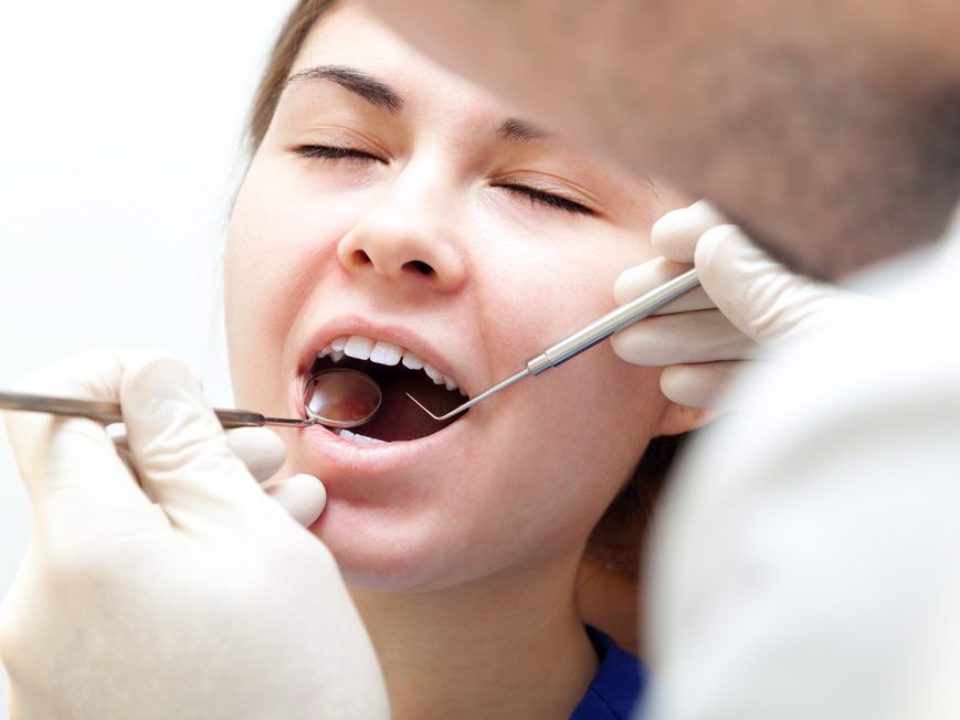 A dentist examining a patient&rsquo;s teeth with a mouth mirror and probe