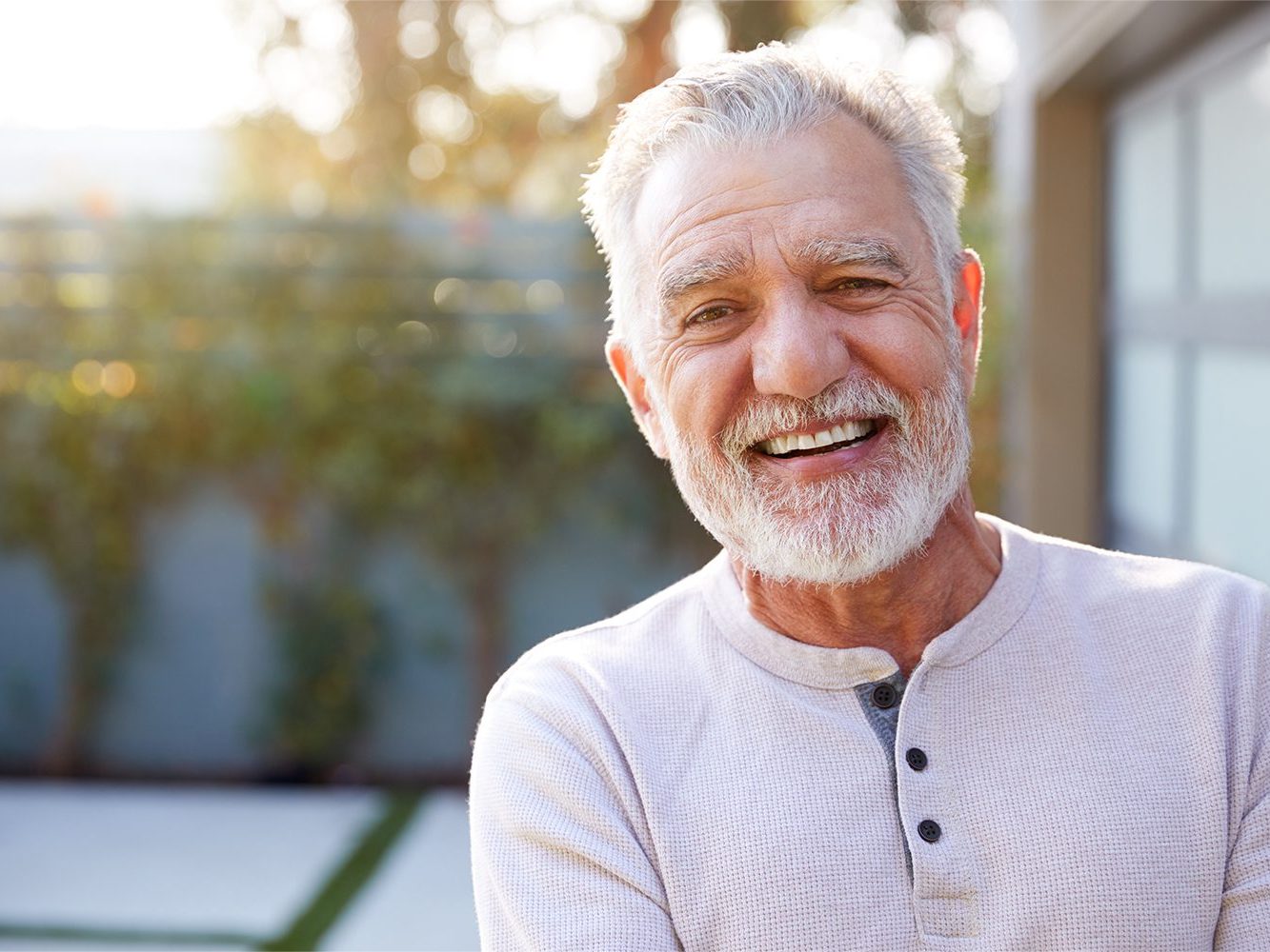 An older man smiling confidently outdoors