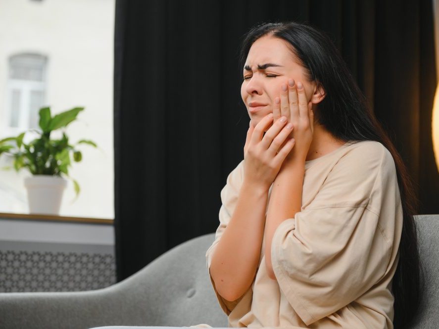 A woman holding her cheek with severe toothache