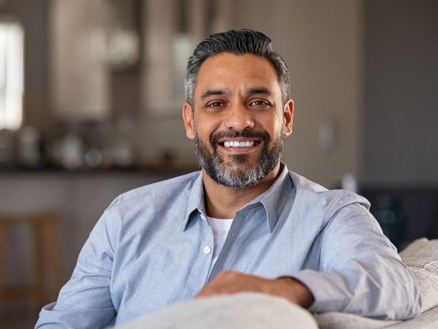 A smiling man relaxing on a sofa at home