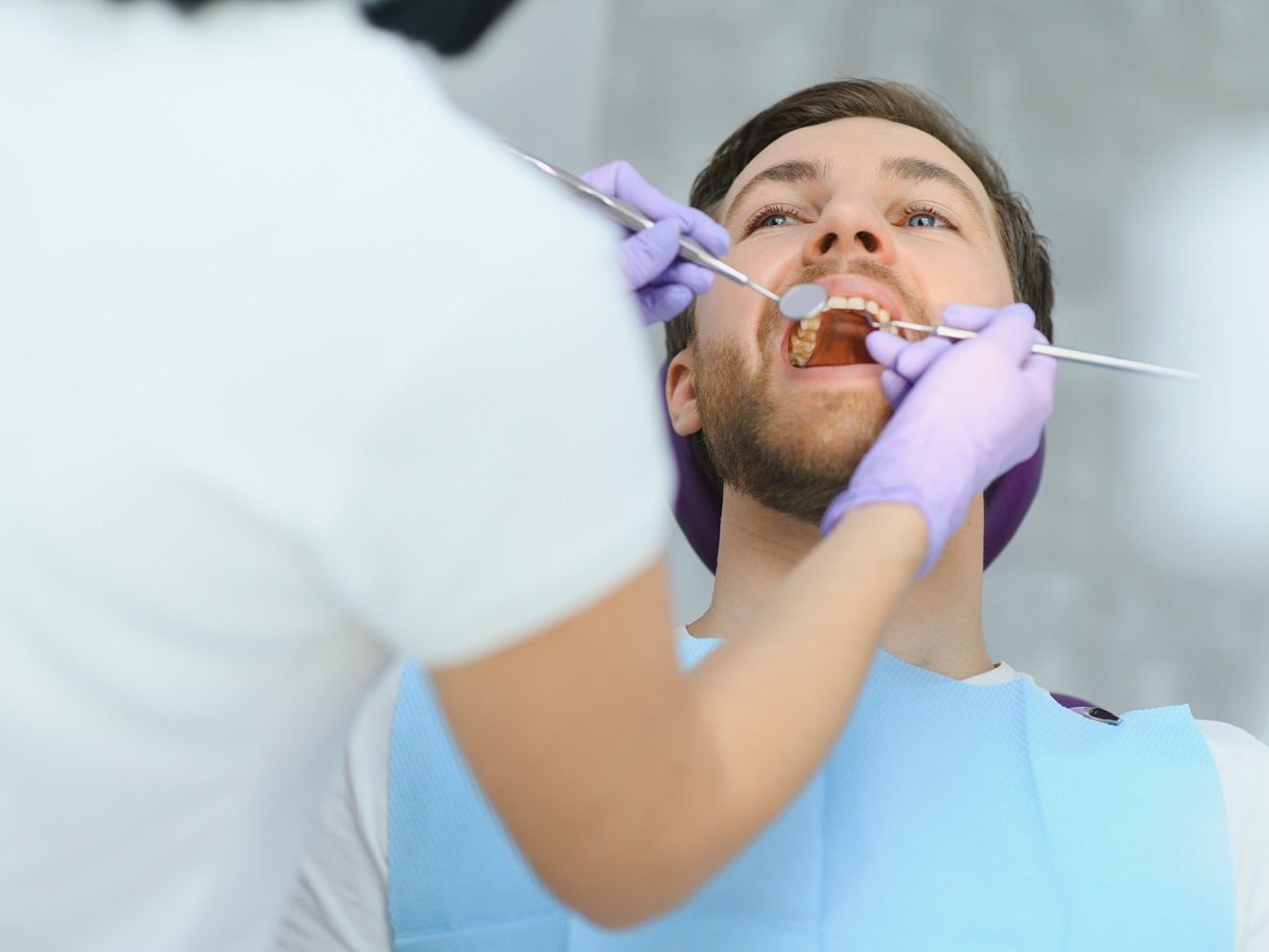 A dentist examining a patient&rsquo;s gums