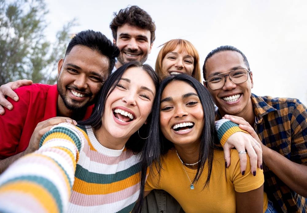 Group of friends smiling together outdoors - Rancho Bernardo Dentist Diverse group of young adults taking a selfie while smiling brightly, representing healthy smiles - Rancho Bernardo Dentist