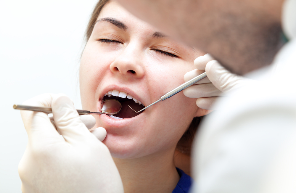 Woman undergoing dental procedure - Tooth Extraction Rancho Bernardo A female patient with mouth open during a dental exam, receiving professional care for tooth extraction - Tooth Extraction Rancho Bernardo