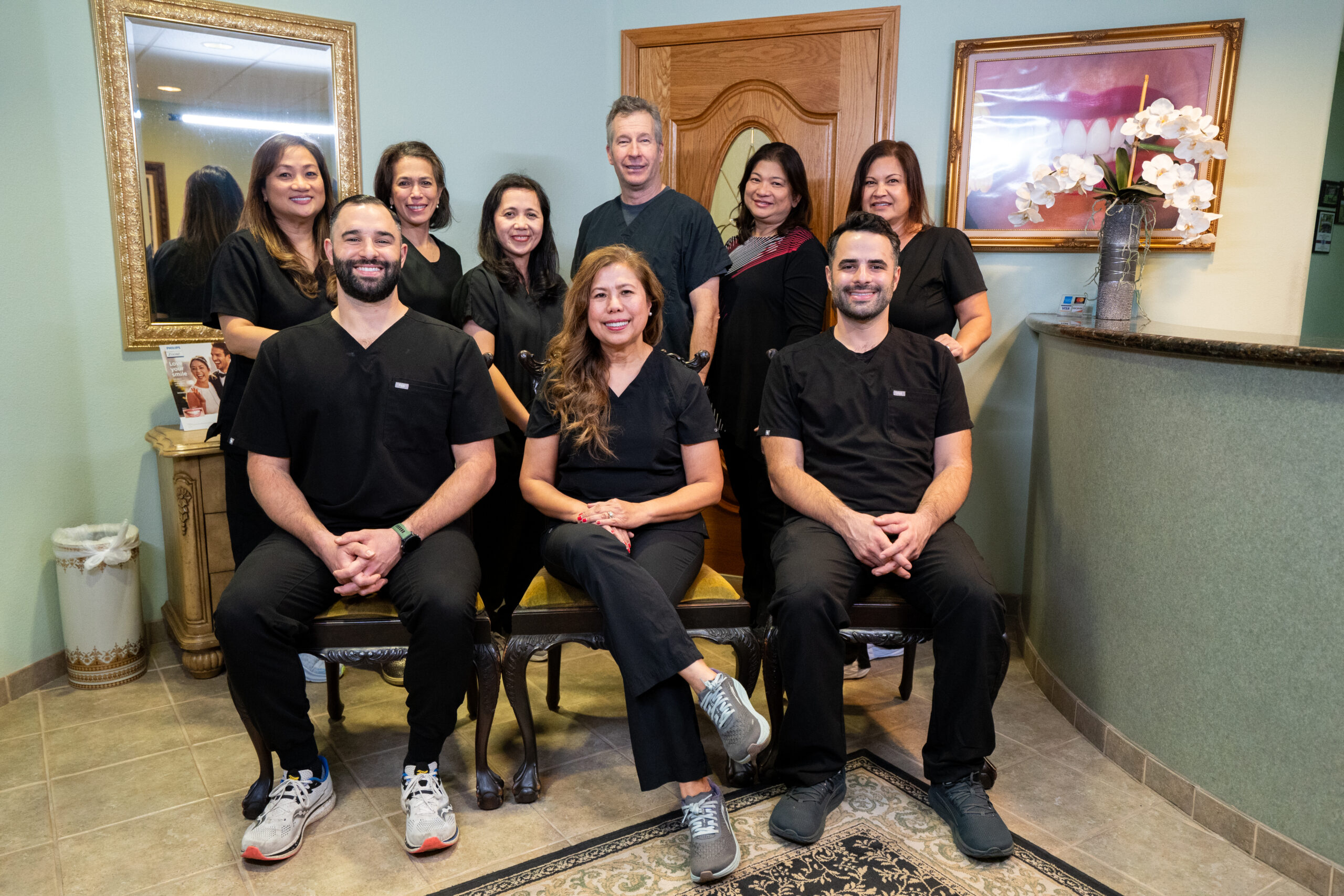 Dental care team group photo - Anchor Dental & Implant Center Professional dental team smiling together in clinic reception area - Anchor Dental & Implant Center